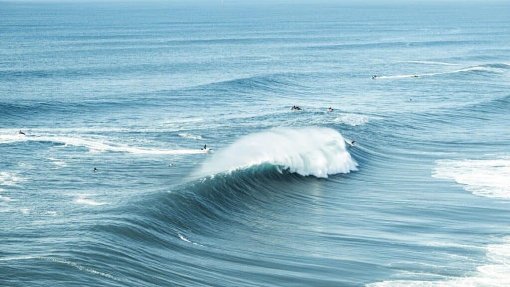 An image of surfers surfing a big wave