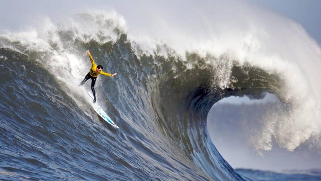 An image of a person surfing Mavericks, a world-renowned big wave surfing spot in Northern California