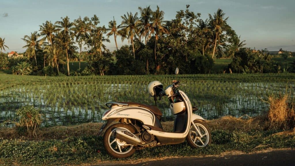 An image of a white moped in Indonesia with an open faced helmet on the handlebars