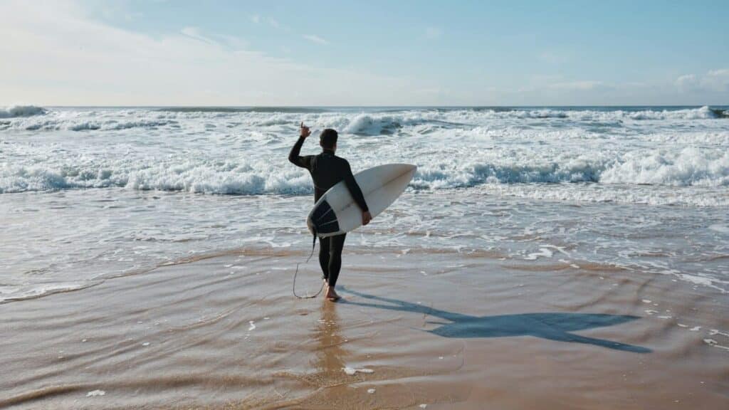 Ein Bild von einem Mann, der mit einem Surfbrett ins Meer geht