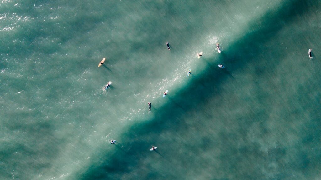 An image of a group of surfers relaxing on their boards in the sea