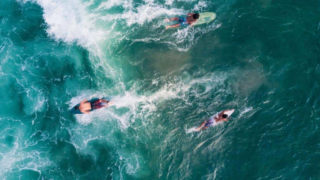 An image of three surfers relaxing on their boards in the sea in Bali